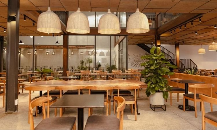 Kh&ocirc;ng gian nh&agrave; h&agrave;ng rộng r&atilde;i, nội thất gỗ, b&agrave;n ghế sắp xếp gọn g&agrave;ng, trang tr&iacute; c&acirc;y xanh v&agrave; đ&egrave;n trần ấm &aacute;p.