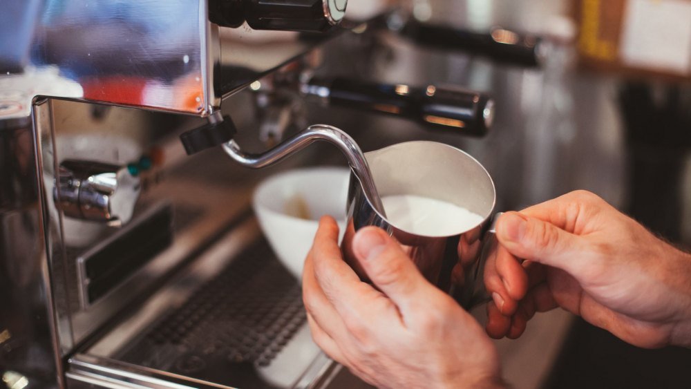 cach-pha-latte-don-gian Người đang pha chế sữa bằng vòi hơi của máy pha cà phê espresso.
