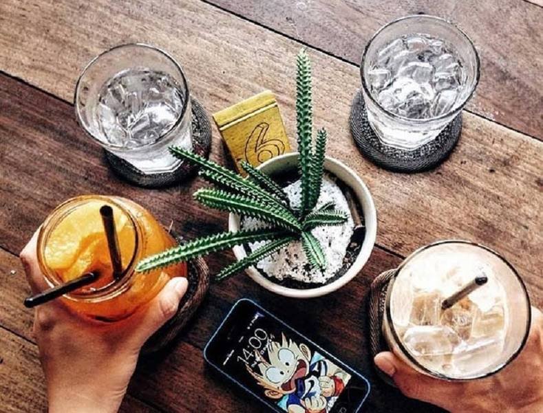 Ba ly nước đ&aacute;, một chậu xương rồng, điện thoại v&agrave; số 6 tr&ecirc;n b&agrave;n gỗ.