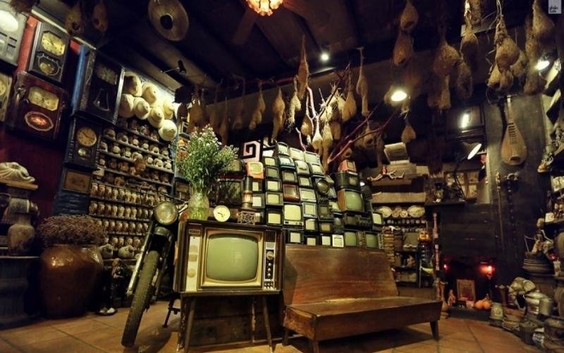 Phòng trưng bày đồ cổ với nhiều tivi cũ, xe máy cổ và các vật dụng trang trí truyền thống.