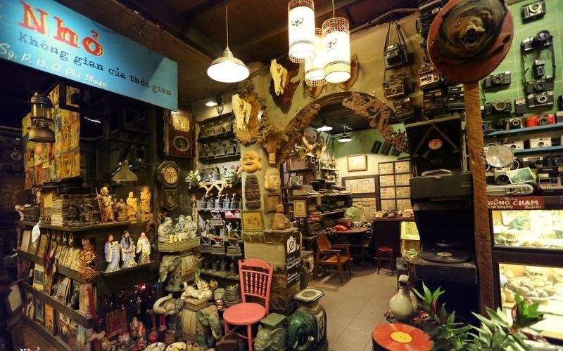 Cửa hàng đồ cổ với nhiều vật trang trí và đồ sưu tầm, ánh sáng ấm áp và không gian cổ điển.