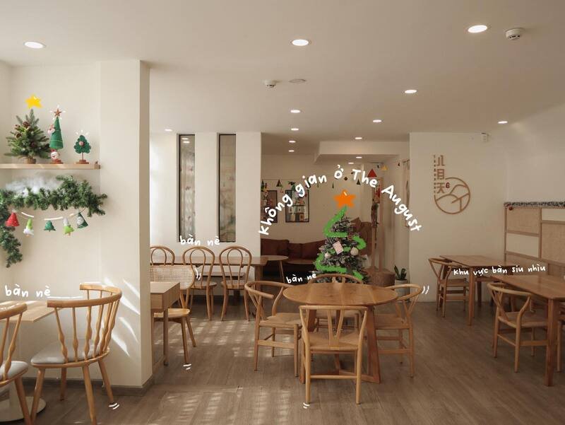 Qu&aacute;n c&agrave; ph&ecirc; trang tr&iacute; c&acirc;y th&ocirc;ng Noel, b&agrave;n ghế gỗ xếp gọn g&agrave;ng trong kh&ocirc;ng gian s&aacute;ng sủa v&agrave; ấm c&uacute;ng.