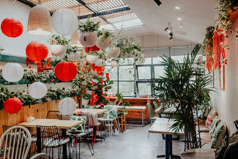 Qu&aacute;n c&agrave; ph&ecirc; trang tr&iacute; đ&egrave;n lồng đỏ trắng, c&acirc;y xanh, b&agrave;n ghế gỗ, kh&ocirc;ng gian s&aacute;ng v&agrave; tho&aacute;ng đ&atilde;ng.