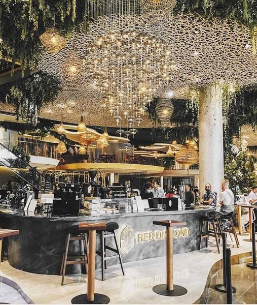 Qu&aacute;n c&agrave; ph&ecirc; sang trọng với nội thất hiện đại, trần nh&agrave; trang tr&iacute; đ&egrave;n lấp l&aacute;nh, kh&aacute;ch h&agrave;ng ngồi thưởng thức đồ uống.