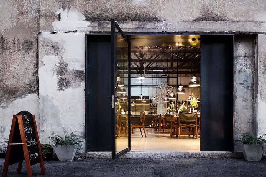 Cửa k&iacute;nh mở ra khung cảnh b&ecirc;n trong nh&agrave; h&agrave;ng với &aacute;nh s&aacute;ng ấm &aacute;p v&agrave; b&agrave;n ghế được sắp xếp gọn g&agrave;ng.