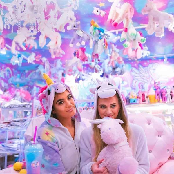 Hai người mặc đồ kỳ l&acirc;n trong qu&aacute;n c&agrave; ph&ecirc; trang tr&iacute; đầy th&uacute; b&ocirc;ng m&agrave;u sắc rực rỡ v&agrave; bắt mắt.