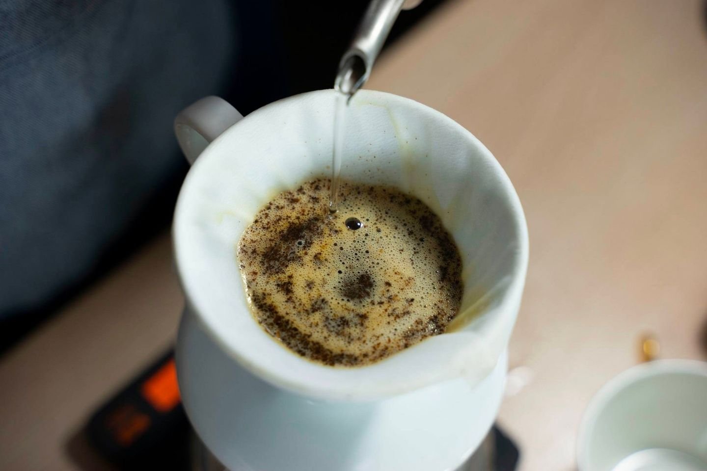 Nước đang được r&oacute;t v&agrave;o phễu lọc c&agrave; ph&ecirc; chứa bột c&agrave; ph&ecirc;, tạo bọt v&agrave; chiết xuất c&agrave; ph&ecirc;.