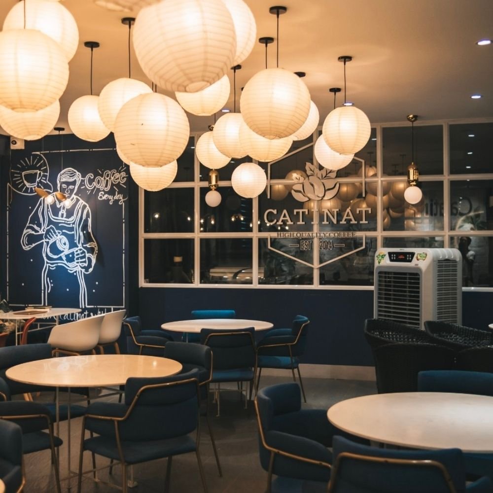 Qu&aacute;n c&agrave; ph&ecirc; với đ&egrave;n lồng giấy treo, b&agrave;n ghế xếp gọn g&agrave;ng, trang tr&iacute; tường c&oacute; h&igrave;nh vẽ v&agrave; chữ "Coffee".