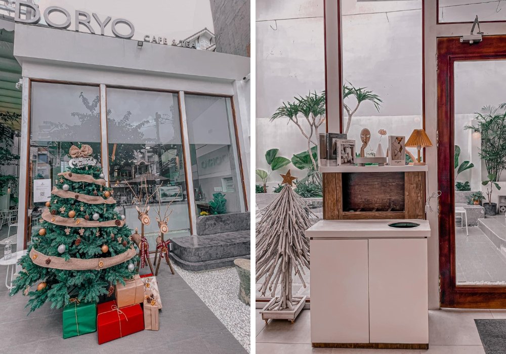 Cây thông Noel trang trí trước quán cà phê; bên trong có kệ gỗ với đèn và trang trí cây nhỏ.