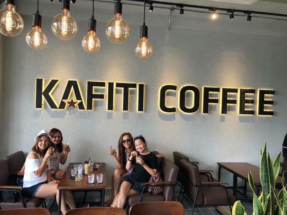 Bốn người ngồi uống cà phê tại quán Kafiti Coffee với không gian trang trí hiện đại và đèn treo sáng.