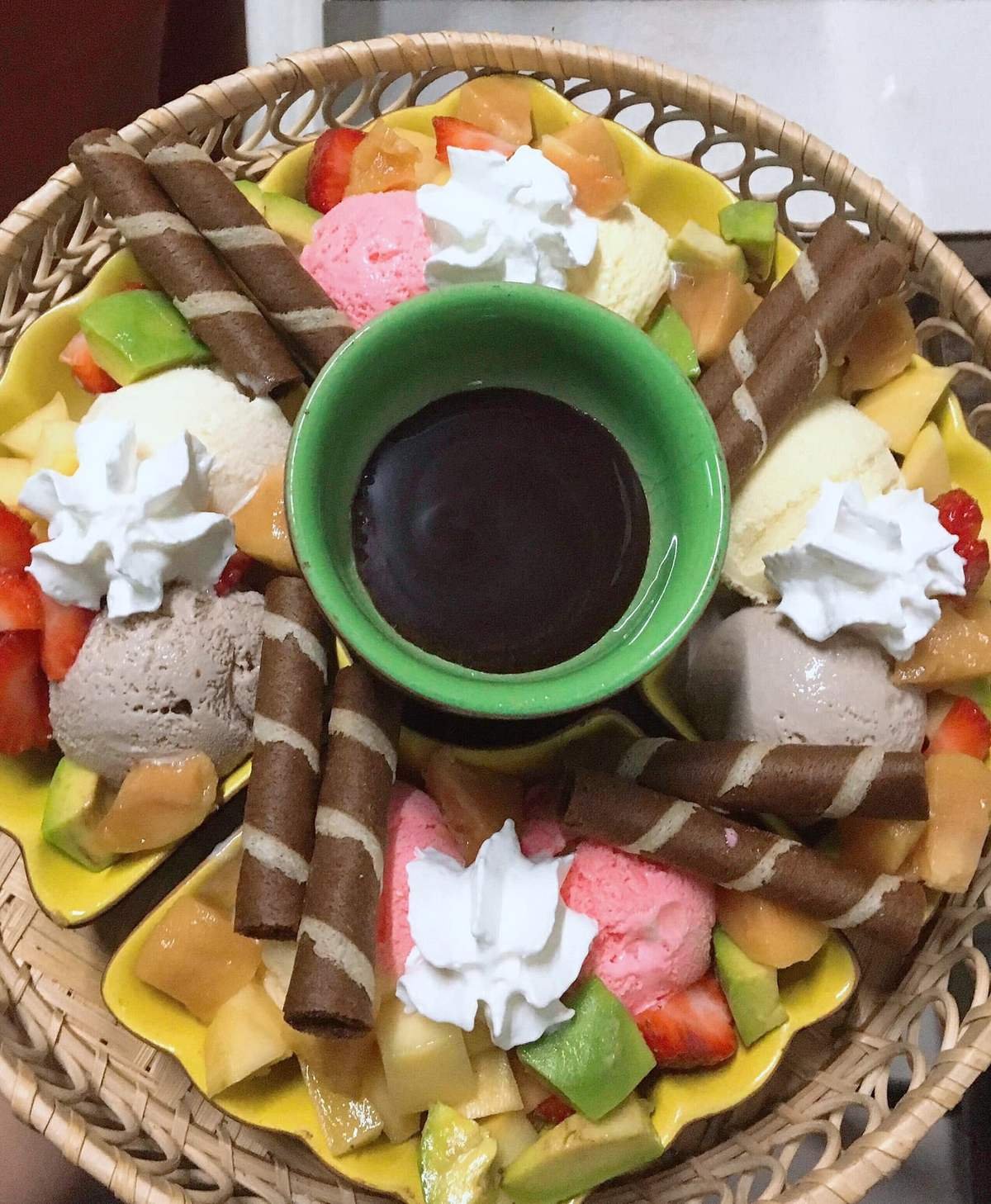 M&oacute;n tr&aacute;ng miệng gồm kem, tr&aacute;i c&acirc;y, b&aacute;nh ống quế, v&agrave; sốt s&ocirc;-c&ocirc;-la trong ch&eacute;n xanh, trang tr&iacute; kem tươi.