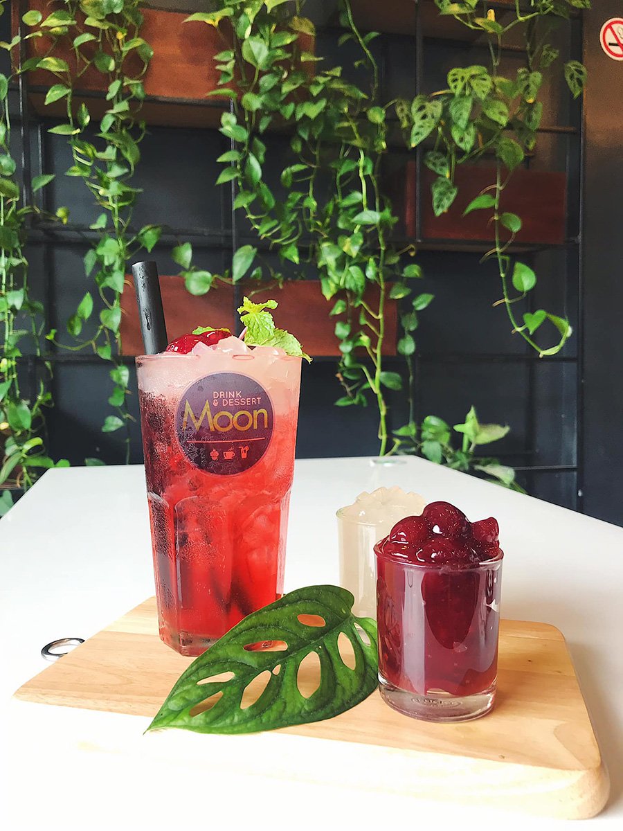 Hai ly nước m&agrave;u đỏ v&agrave; trắng tr&ecirc;n b&agrave;n gỗ, trang tr&iacute; l&aacute; c&acirc;y xanh, nền l&agrave; tường c&acirc;y leo.