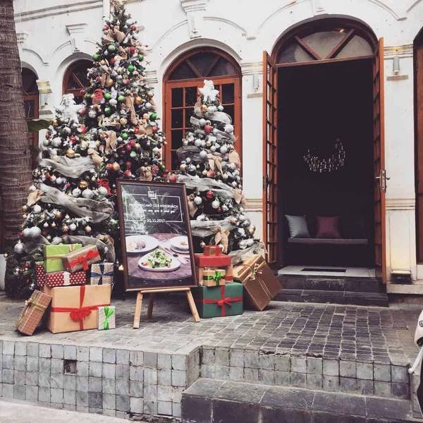 C&acirc;y th&ocirc;ng Noel trang tr&iacute; với hộp qu&agrave; v&agrave; bảng hiệu trước cửa một t&ograve;a nh&agrave; kiến tr&uacute;c cổ điển.