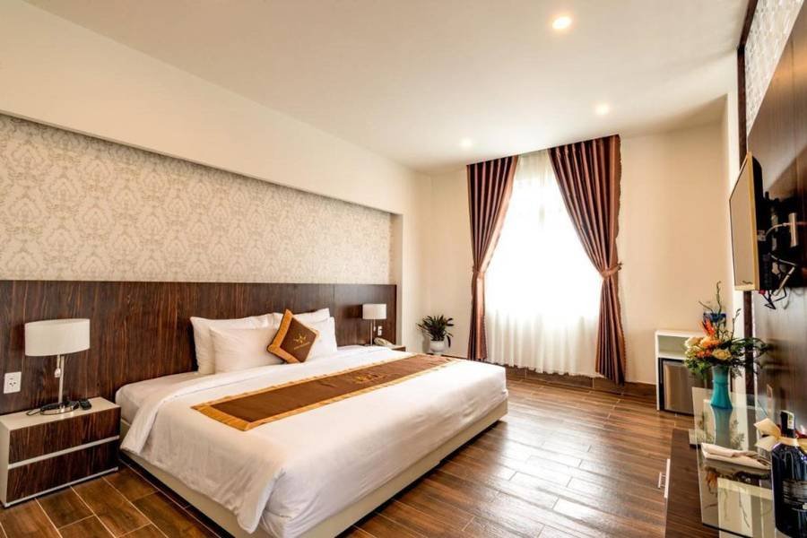 Ph&ograve;ng ngủ kh&aacute;ch sạn với giường đ&ocirc;i, tường s&aacute;ng m&agrave;u, r&egrave;m cửa tối, đ&egrave;n ngủ v&agrave; tivi.