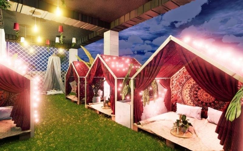 Khu vực ngoài trời với lều trang trí đèn lấp lánh và rèm đỏ, tạo không gian ấm cúng và lãng mạn.