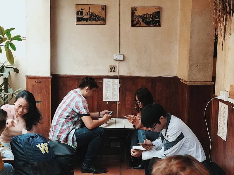 Nh&oacute;m người ngồi trong qu&aacute;n c&agrave; ph&ecirc;, mỗi người đều sử dụng điện thoại di động.