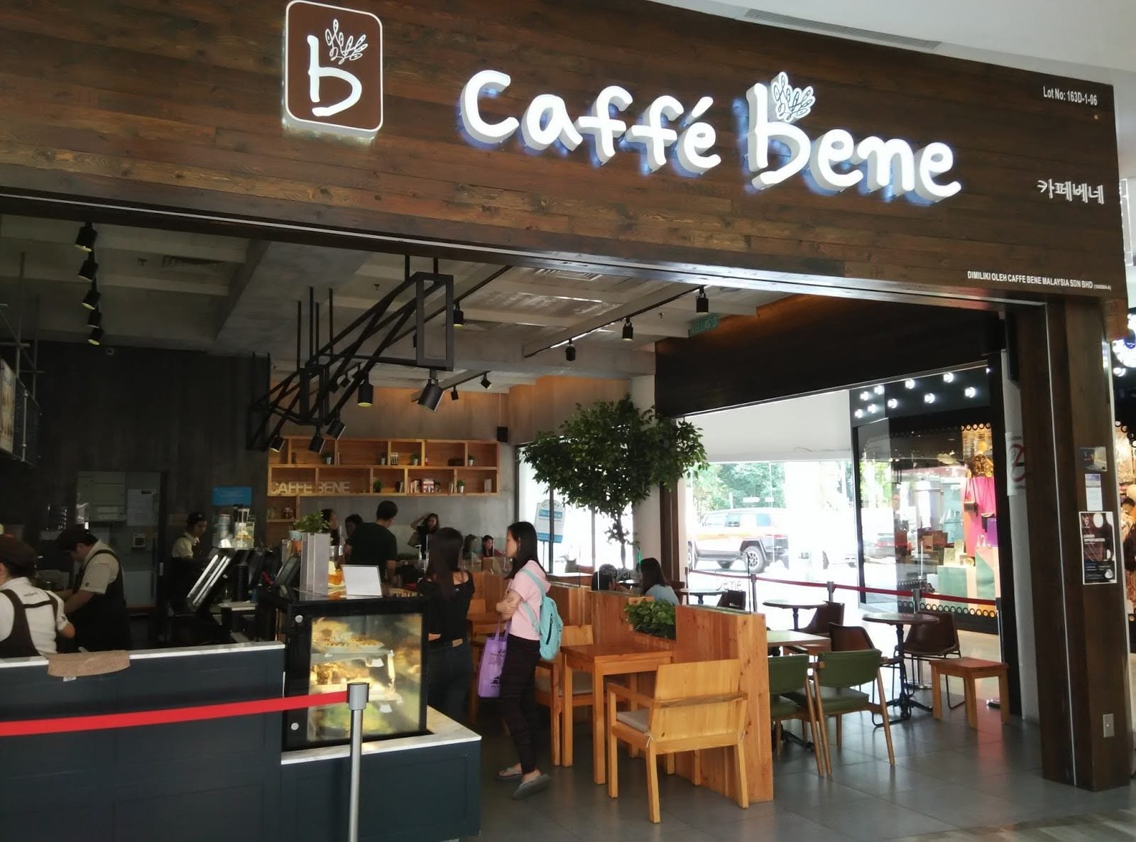 Top 32 thương hiệu nhượng quyền cafe siêu lợi nhuận 17 Quán cà phê với nội thất gỗ, có khách hàng đứng chờ và nhân viên phục vụ phía sau quầy pha chế.