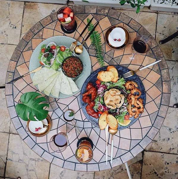 B&agrave;n ăn với đĩa thức ăn đa dạng gồm rau, thịt v&agrave; b&aacute;nh m&igrave;, c&ugrave;ng ly nước v&agrave; trang tr&iacute; l&aacute; xanh.