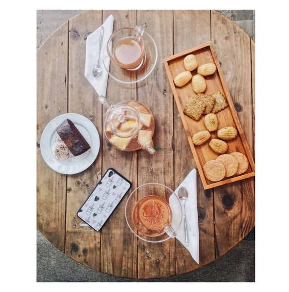 B&agrave;n gỗ tr&ograve;n với tr&agrave;, b&aacute;nh ngọt, smartphone v&agrave; b&aacute;nh quy tr&ecirc;n khay gỗ, tạo cảm gi&aacute;c ấm c&uacute;ng v&agrave; thư gi&atilde;n.