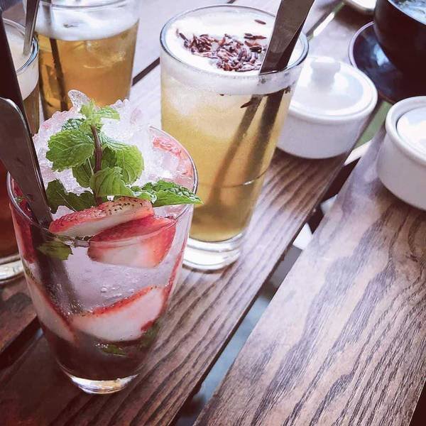 Ba ly nước giải kh&aacute;t tr&ecirc;n b&agrave;n gỗ, gồm tr&agrave; đ&aacute; v&agrave; nước tr&aacute;i c&acirc;y với d&acirc;u t&acirc;y v&agrave; l&aacute; bạc h&agrave;.