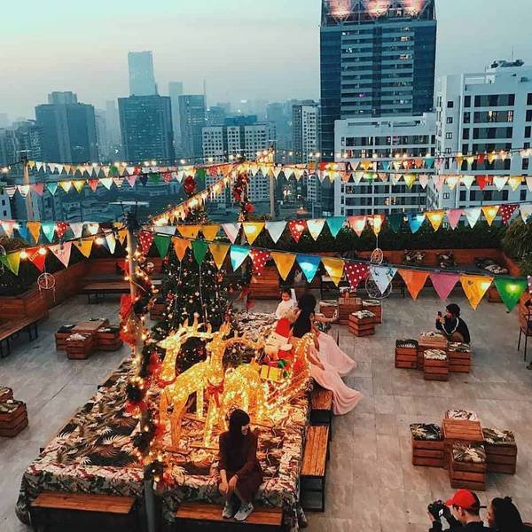 S&acirc;n thượng được trang tr&iacute; với đ&egrave;n, cờ v&agrave; c&acirc;y th&ocirc;ng Noel, mọi người ngồi tr&ograve; chuyện xung quanh.