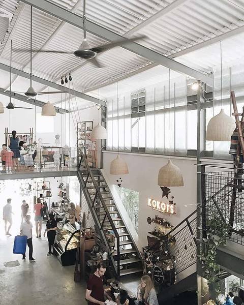 Qu&aacute;n c&agrave; ph&ecirc; hai tầng với nội thất hiện đại, c&oacute; cầu thang giữa, kh&aacute;ch h&agrave;ng đang tr&ograve; chuyện v&agrave; thưởng thức đồ uống.