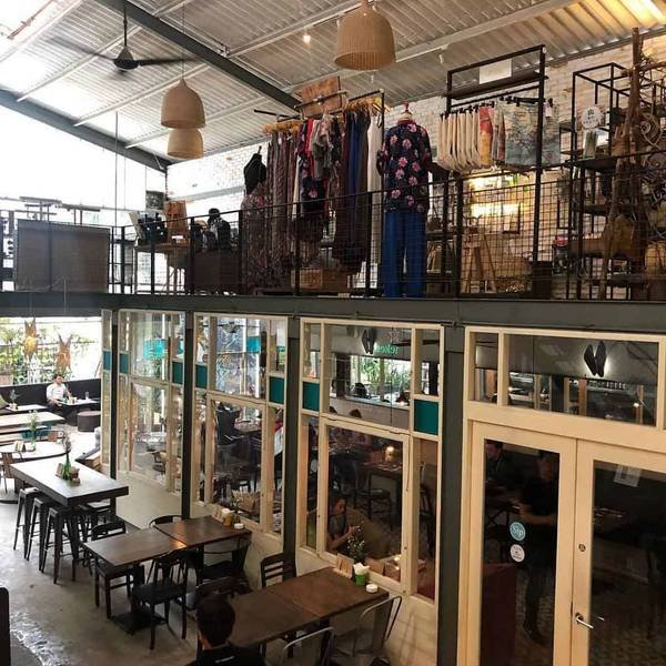 Kh&ocirc;ng gian qu&aacute;n c&agrave; ph&ecirc; hai tầng, tầng tr&ecirc;n trưng b&agrave;y quần &aacute;o, tầng dưới c&oacute; b&agrave;n ghế gỗ, &aacute;nh s&aacute;ng tự nhi&ecirc;n.