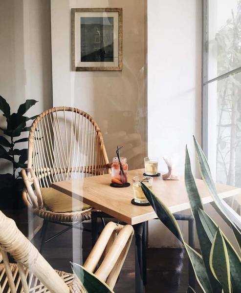 G&oacute;c qu&aacute;n c&agrave; ph&ecirc; với b&agrave;n gỗ, ghế m&acirc;y, đồ uống v&agrave; c&acirc;y xanh trang tr&iacute;, tạo kh&ocirc;ng gian thư gi&atilde;n v&agrave; thoải m&aacute;i.