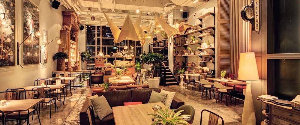 Kh&ocirc;ng gian qu&aacute;n c&agrave; ph&ecirc; với &aacute;nh s&aacute;ng ấm &aacute;p, nội thất hiện đại, b&agrave;n ghế gỗ v&agrave; c&acirc;y xanh trang tr&iacute;.