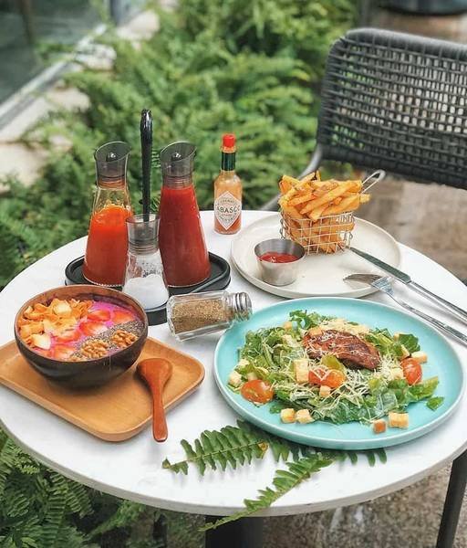 B&agrave;n ăn ngo&agrave;i trời với salad, khoai t&acirc;y chi&ecirc;n, b&uacute;n v&agrave; nước sốt. Đồ ăn được b&agrave;y tr&iacute; đẹp mắt tr&ecirc;n b&agrave;n tr&ograve;n.