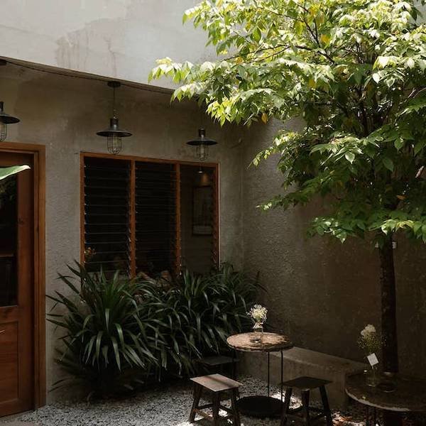 Khoảng s&acirc;n nhỏ với b&agrave;n ghế gỗ, c&acirc;y xanh v&agrave; cửa sổ, tạo cảm gi&aacute;c y&ecirc;n b&igrave;nh v&agrave; tho&aacute;ng đ&atilde;ng.