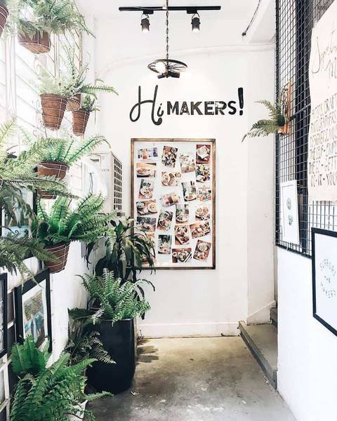 Hành lang trang trí cây xanh, bảng ảnh và chữ "Hi Makers!" trên tường.