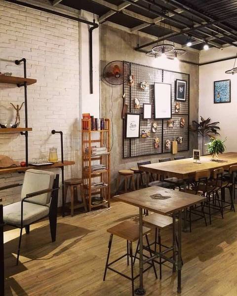 Quán cà phê với nội thất gỗ, tường gạch trắng, và tranh trang trí. Không gian ấm cúng và hiện đại.