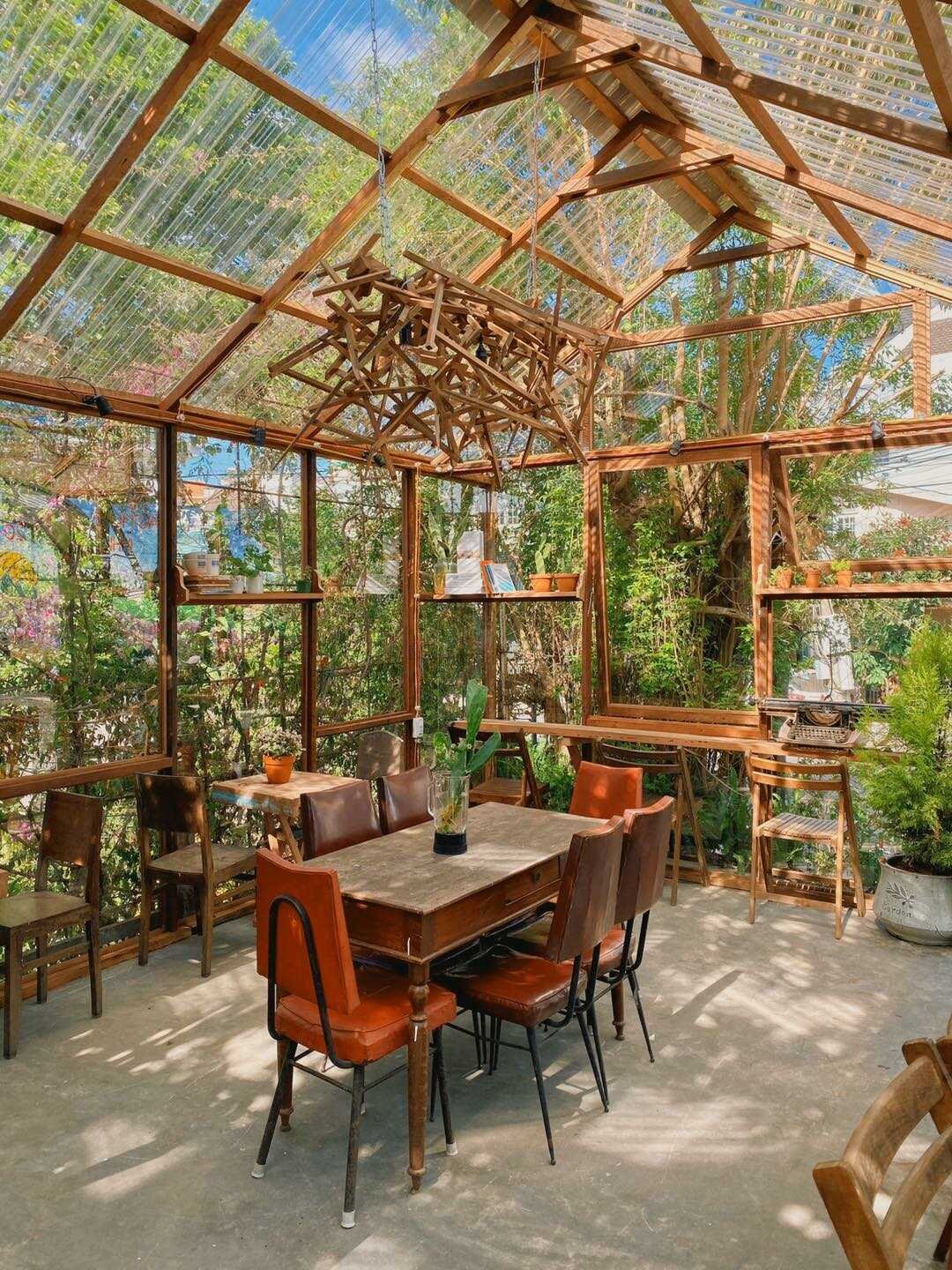 Nh&agrave; k&iacute;nh với b&agrave;n ghế gỗ, &aacute;nh s&aacute;ng tự nhi&ecirc;n, c&acirc;y xanh xung quanh, tạo kh&ocirc;ng gian tho&aacute;ng đ&atilde;ng v&agrave; gần gũi với thi&ecirc;n nhi&ecirc;n.