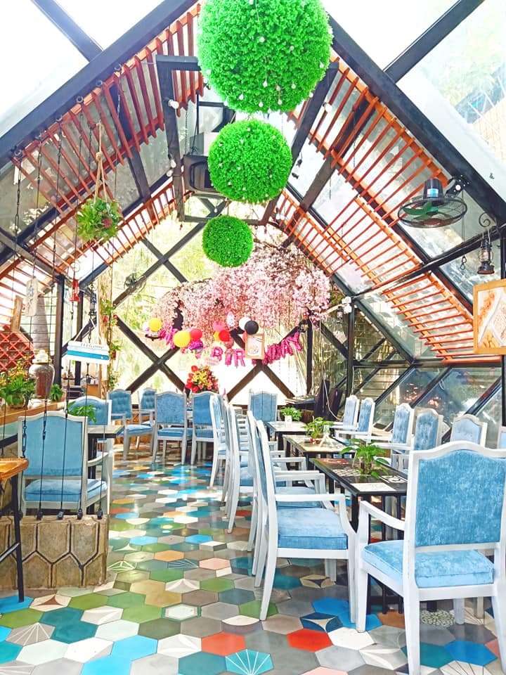 Nh&agrave; k&iacute;nh trang tr&iacute; với b&oacute;ng xanh, hoa anh đ&agrave;o giả, ghế xanh, b&agrave;n d&agrave;i, s&agrave;n gạch lục gi&aacute;c nhiều m&agrave;u.