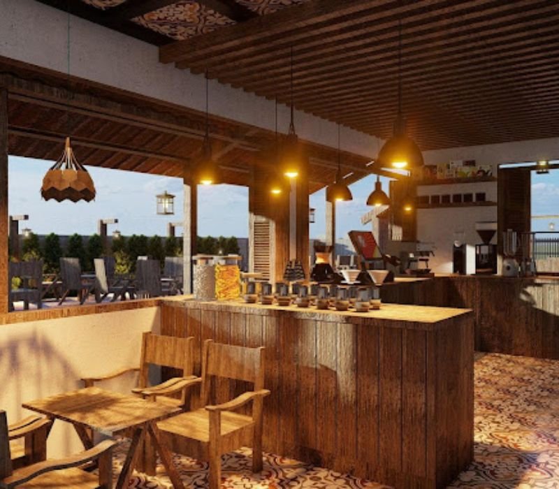 Qu&aacute;n c&agrave; ph&ecirc; ngo&agrave;i trời với b&agrave;n ghế gỗ, &aacute;nh s&aacute;ng ấm &aacute;p v&agrave; quầy pha chế, nh&igrave;n ra cảnh quan xanh m&aacute;t.