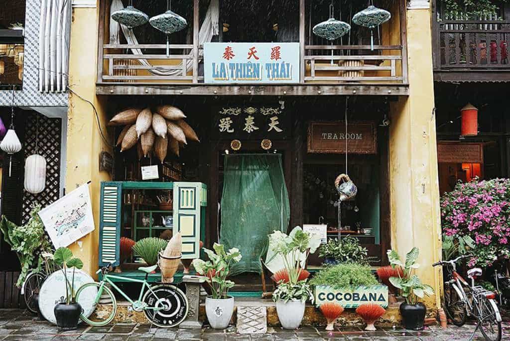 Ảnh: @dulichhoian Mặt tiền quán trà phong cách cổ điển với nhiều cây cảnh và xe đạp trang trí phía trước.