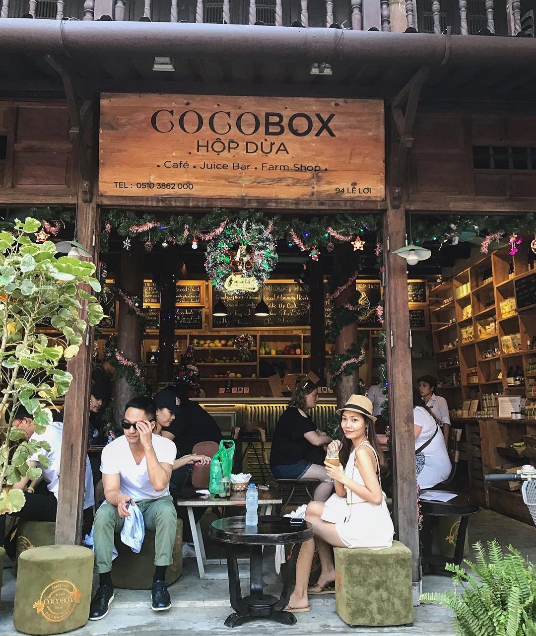 Ảnh: @choco2809 Quán cà phê Cocobox với nhiều người ngồi bên ngoài, khung cảnh trang trí và thực đơn viết trên bảng đen.