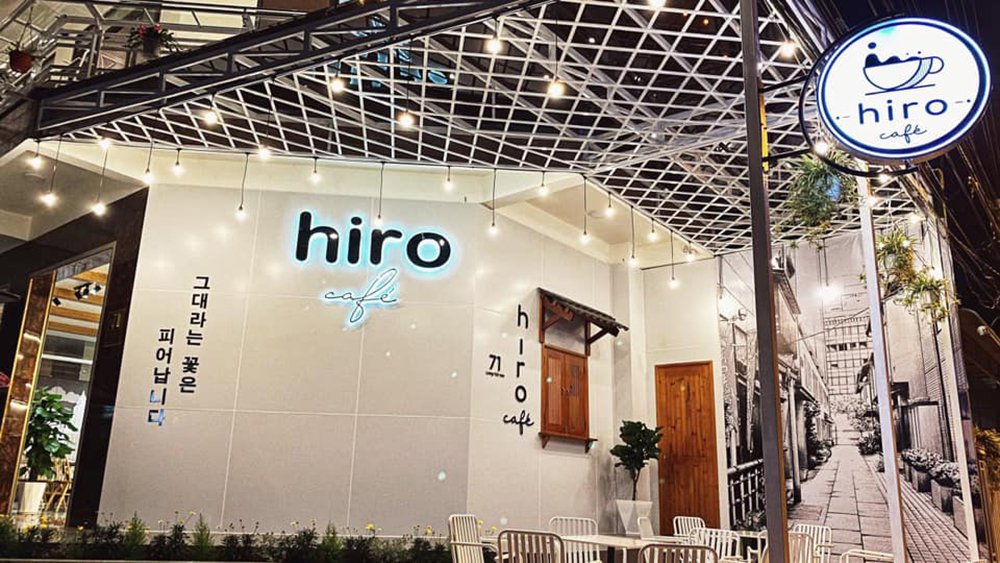 Mặt tiền quán cà phê với biển hiệu "hiro cafe", trang trí ánh sáng và cây xanh, phong cách hiện đại.