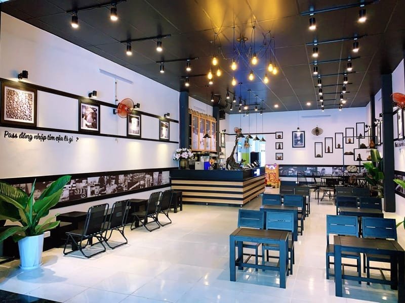 Nhượng quyền cafe Milano có chi phí bao nhiêu? Có nên không? 2 Quán cà phê trang trí hiện đại với bàn ghế gỗ, đèn treo và tranh ảnh trên tường.