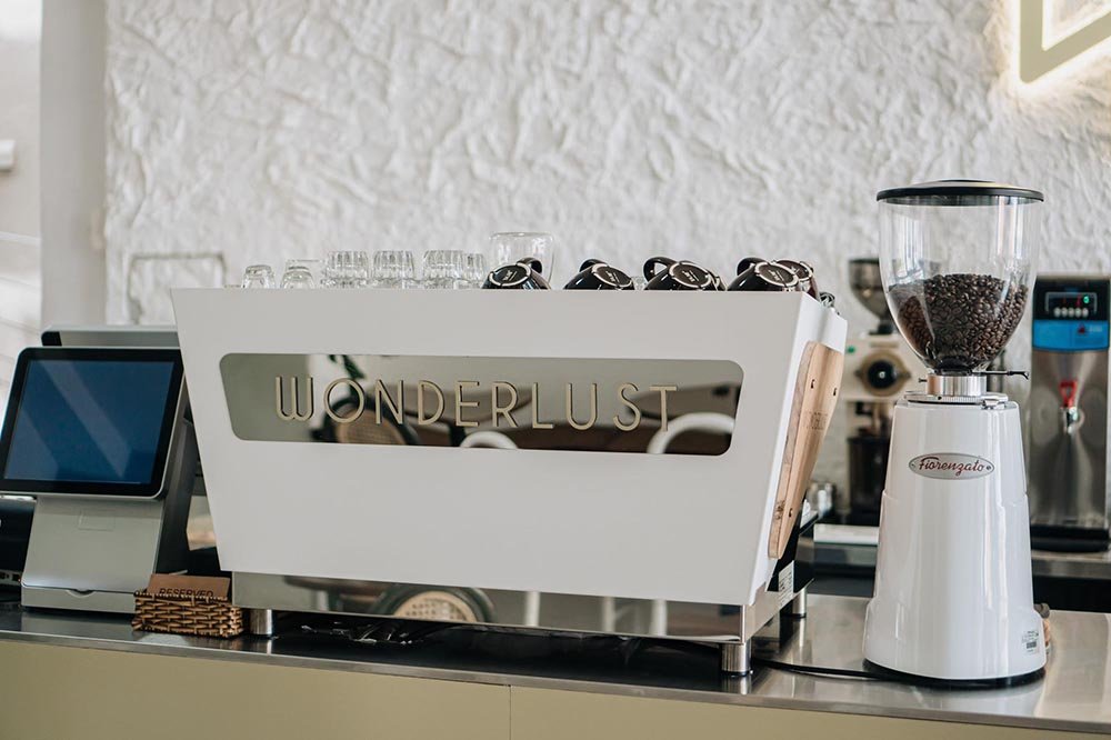 M&aacute;y pha c&agrave; ph&ecirc; v&agrave; m&aacute;y xay đặt tr&ecirc;n quầy, cạnh m&agrave;n h&igrave;nh cảm ứng, trong kh&ocirc;ng gian qu&aacute;n c&agrave; ph&ecirc;.