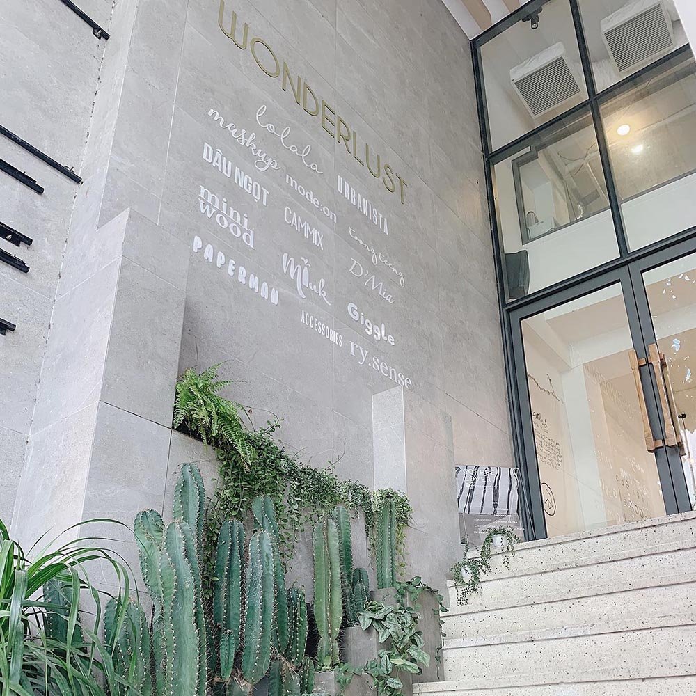 Cầu thang dẫn l&ecirc;n cửa k&iacute;nh lớn, b&ecirc;n cạnh c&oacute; c&aacute;c loại c&acirc;y xương rồng v&agrave; d&ograve;ng chữ trang tr&iacute; tr&ecirc;n tường.